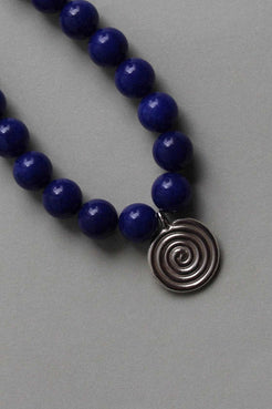 Close-up of vivid blue chalcedony beads and recycled sterling silver Eddy Swirl pendant on a minimal beaded necklace.