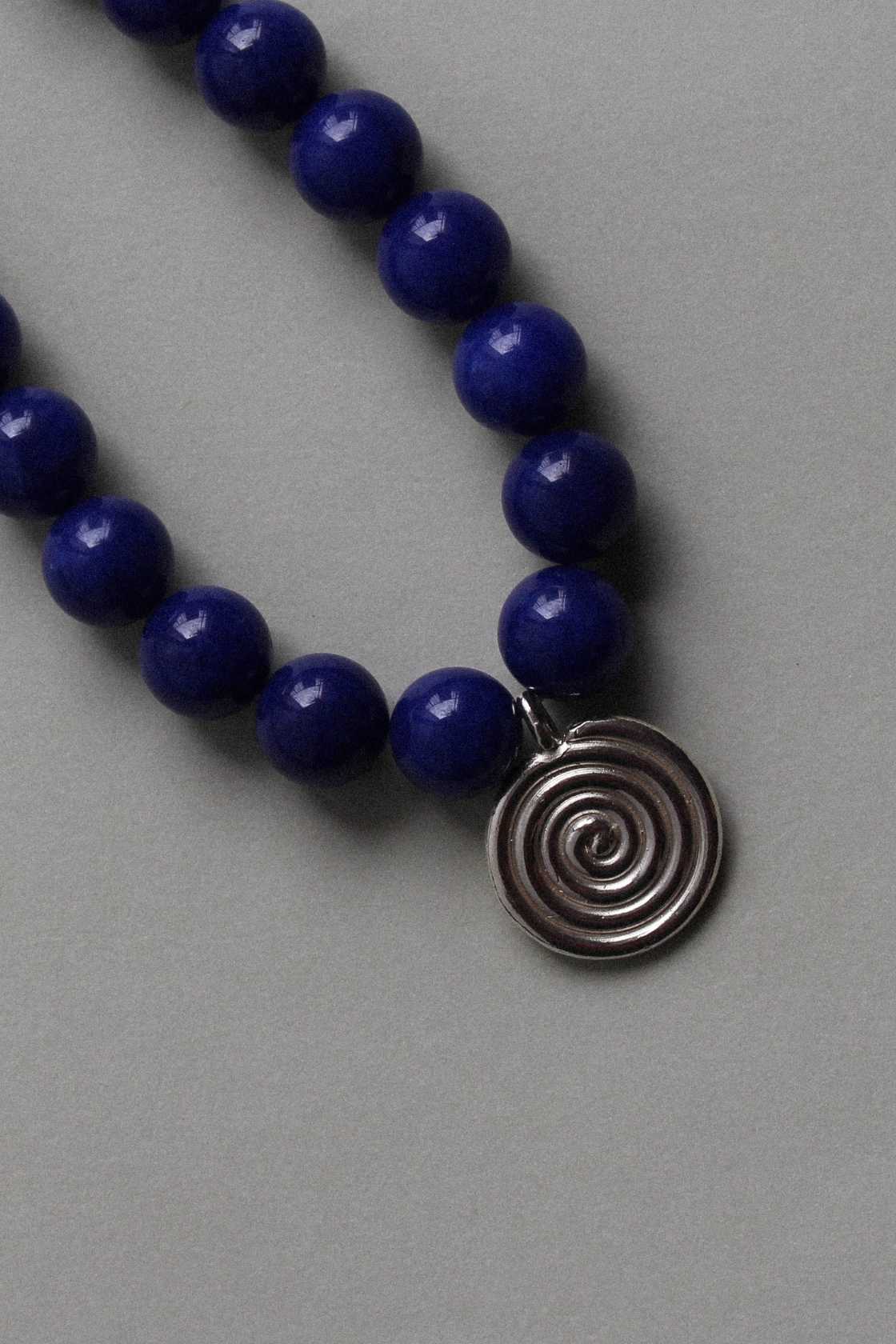 Close-up of vivid blue chalcedony beads and recycled sterling silver Eddy Swirl pendant on a minimal beaded necklace.