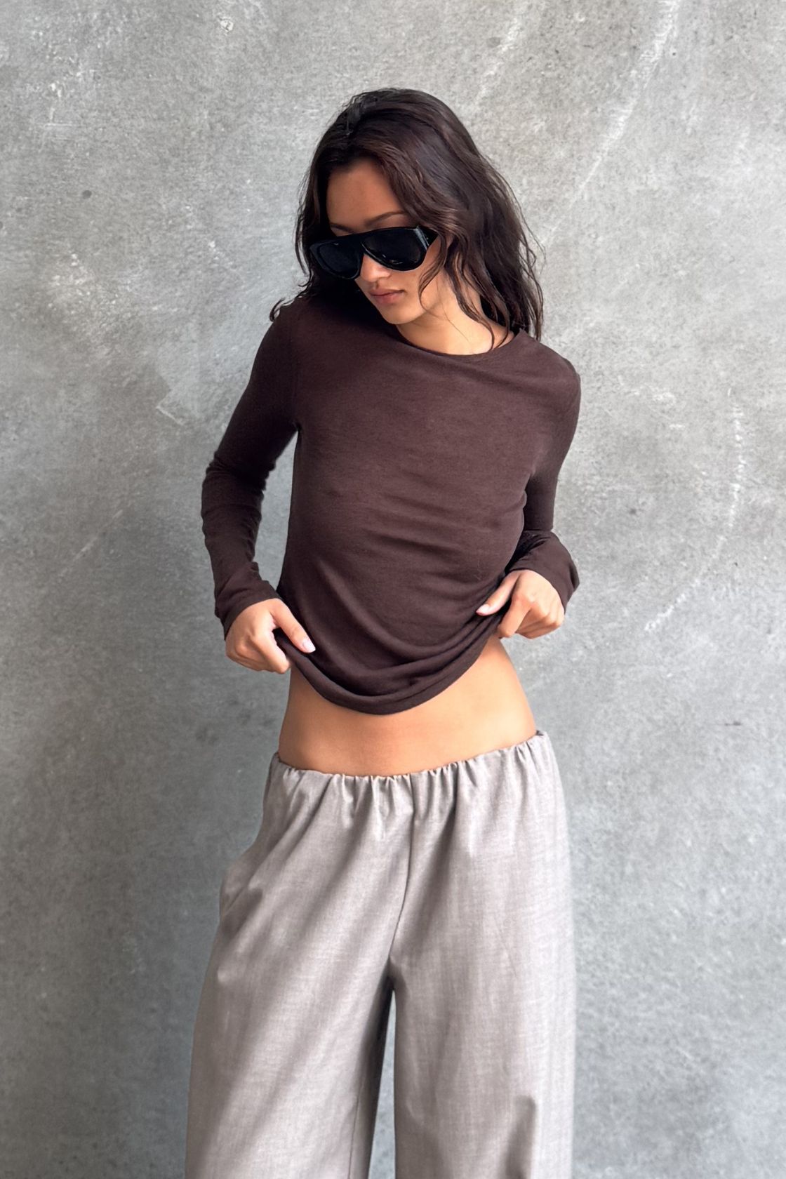Model wearing the Aston Long Sleeve Top in Espresso, a fitted lightweight layering piece with a soft drape, boat neckline and full-length sleeves, styled with the Annika Pant in Taupe & Blue Pinstripe.