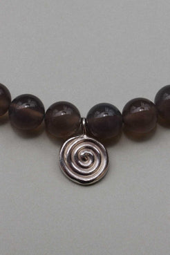 Close-up of taupe grey agate beads with a recycled sterling silver Eddy Swirl pendant on a minimal beaded necklace.