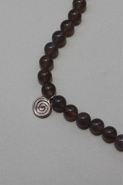 Taupe grey agate beaded necklace shown in a soft curve, highlighting the sterling silver Eddy Swirl pendant against a neutral background.