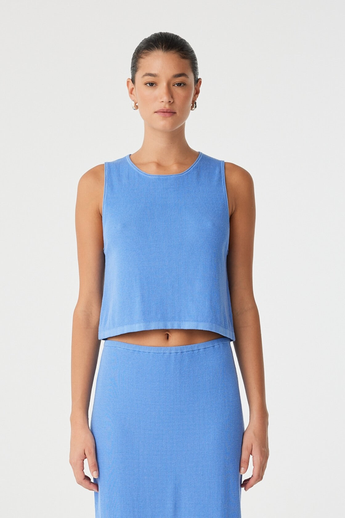 Model wears ribbed knit tank in pacific blue with flared hem, styled with matching skirt in lightweight cotton–hemp blend.