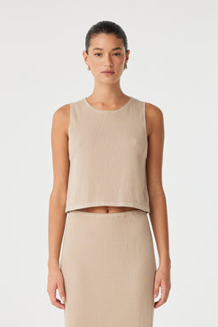 Model wears ribbed knit tank in taupe organic cotton–hemp blend with flared hem—styled as part of a minimal matching set.