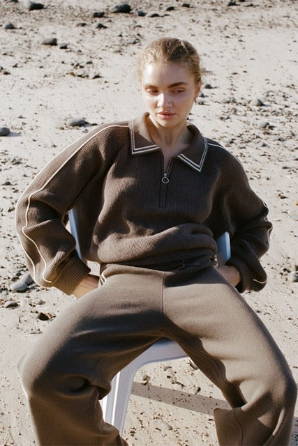 Lifestyle image of brown zip sweater and pants worn outdoors on the beach