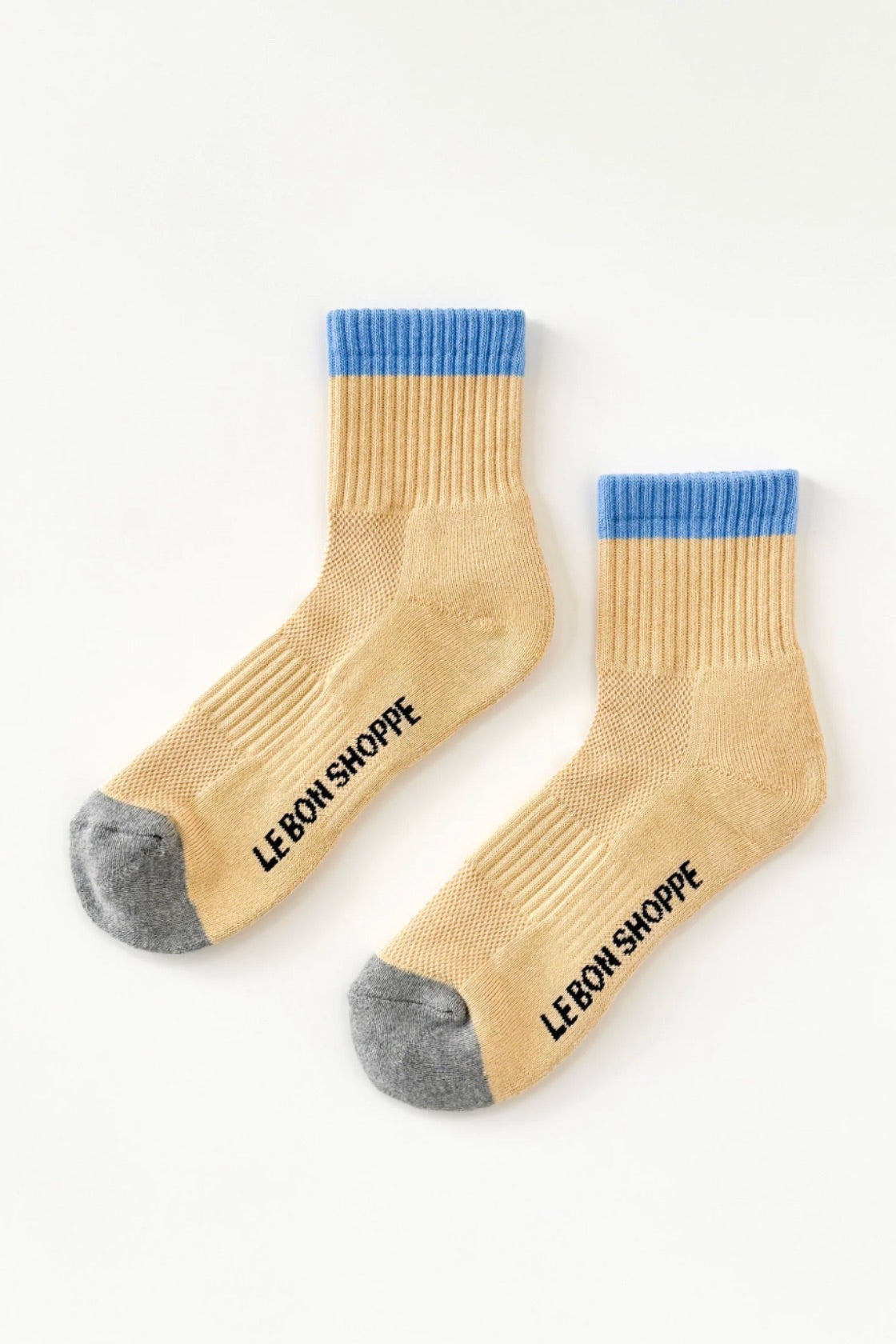 Pair of yellow socks with blue accents and 'LE BON SHOPPE' branding on a white background