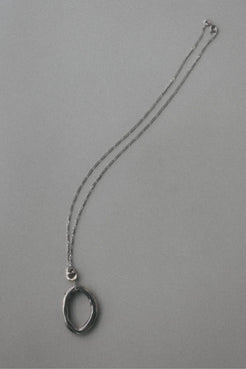 A silver-toned necklace featuring a textured, open oval pendant, displayed on a plain gray background.