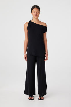 Front view of model wearing black relaxed wide-leg linen organic cotton pants with one-shoulder top