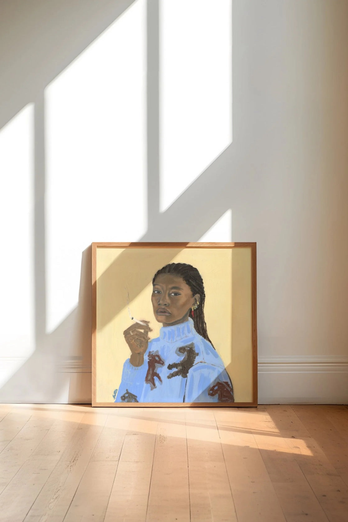 A framed portrait painting of a woman in a light blue sweater with dark patches, leaning against a white wall on a light wood floor. Strong diagonal sunlight and shadows from a window fall across the wall and floor.