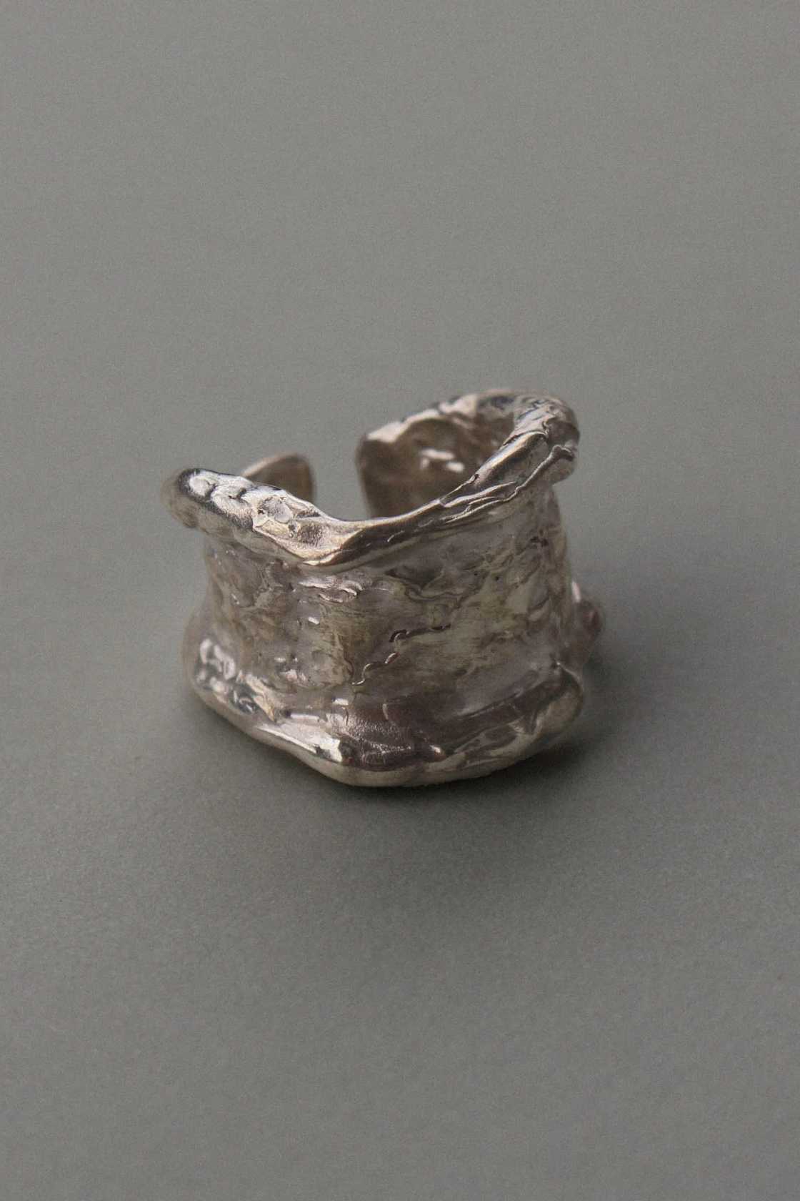 Chunky molten 925 sterling silver ring with organic texture, styled on a neutral surface.