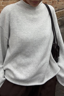Close-up detail view of the Maeve Sweater in snow marle highlighting the soft marled knit texture, relaxed drape through the body and rolled hem and neckline finish styled with espresso pants