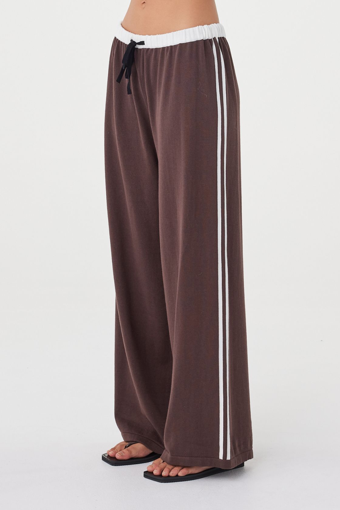 Close-up side view of the Tully Pant in espresso highlighting the organic cotton knit texture, contrast double stripe detail and relaxed straight wide-leg shape