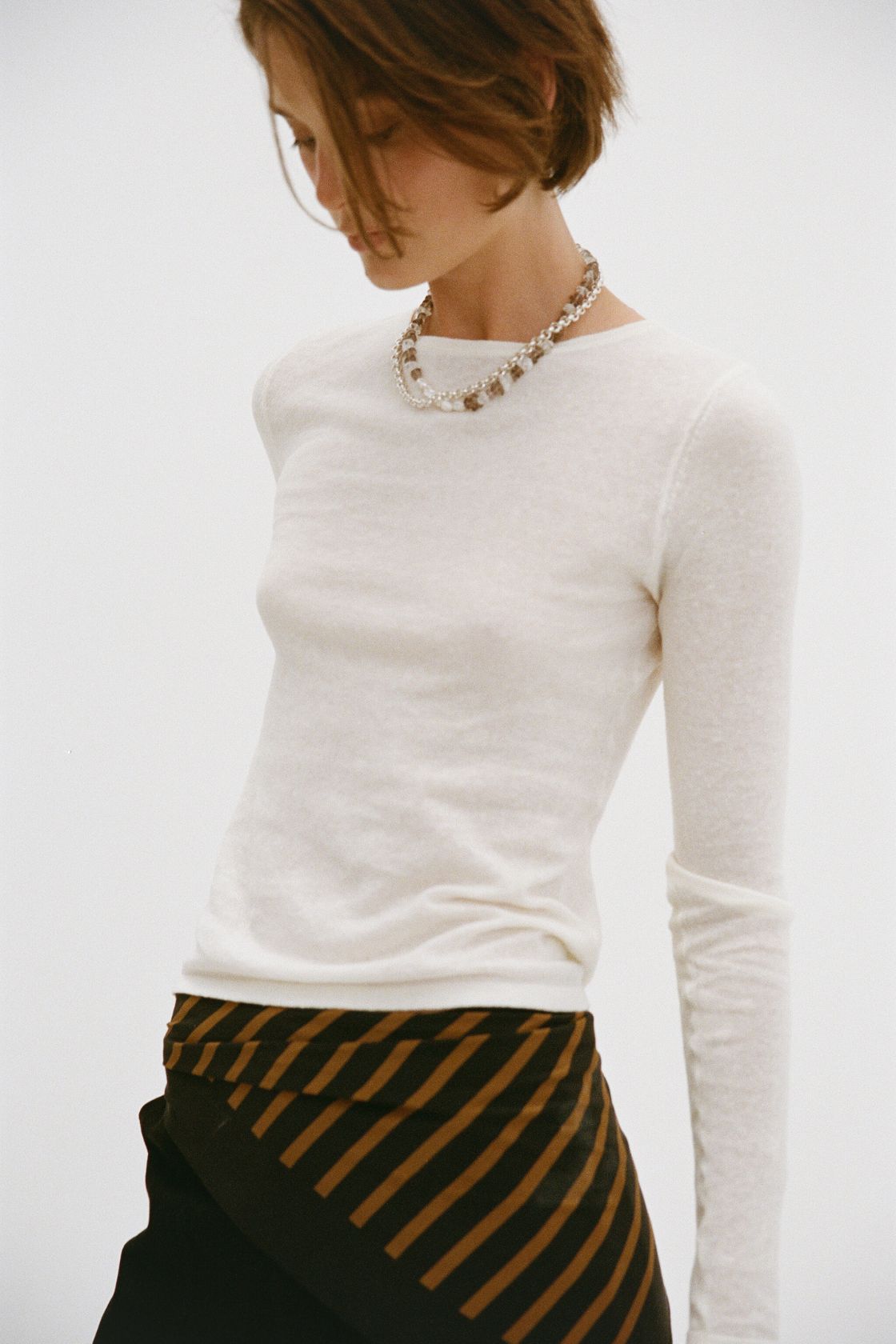 Close detail of Aston Top cream, semi-sheer knit texture with boat neckline and long sleeve.