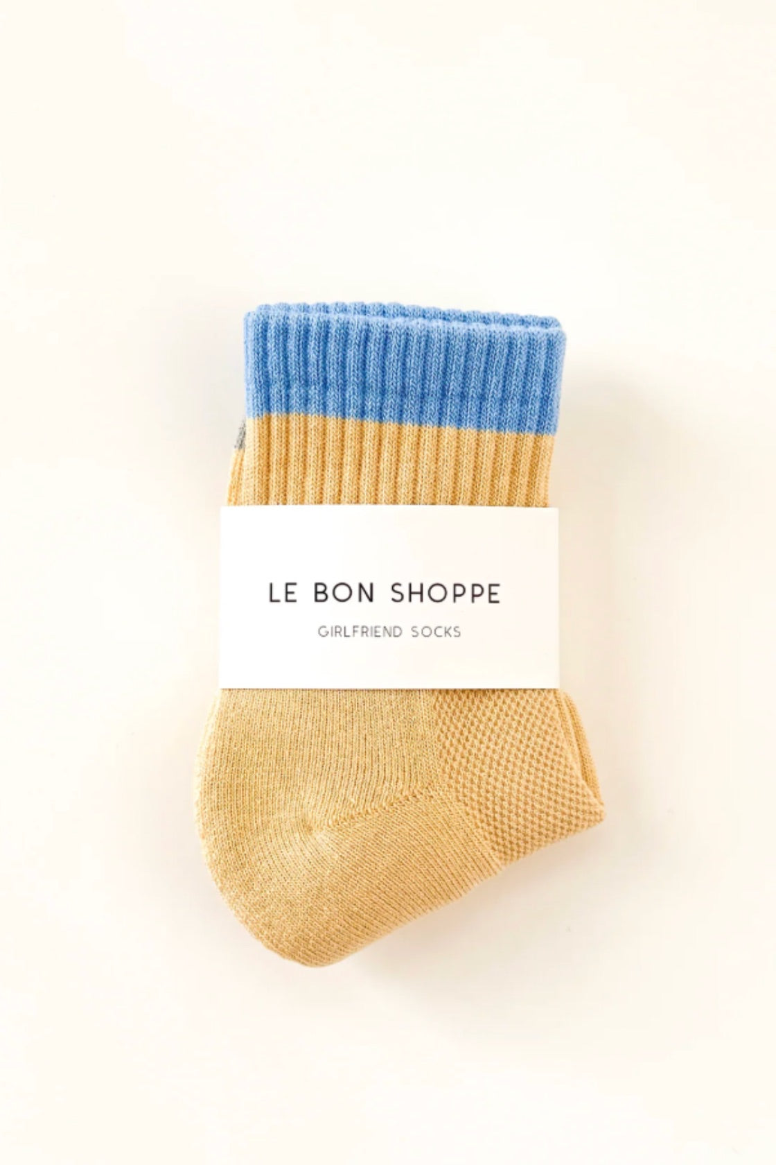 Pair of socks with blue top and yellow bottom on a white background, branded 'Le Bon Shoppe'.
