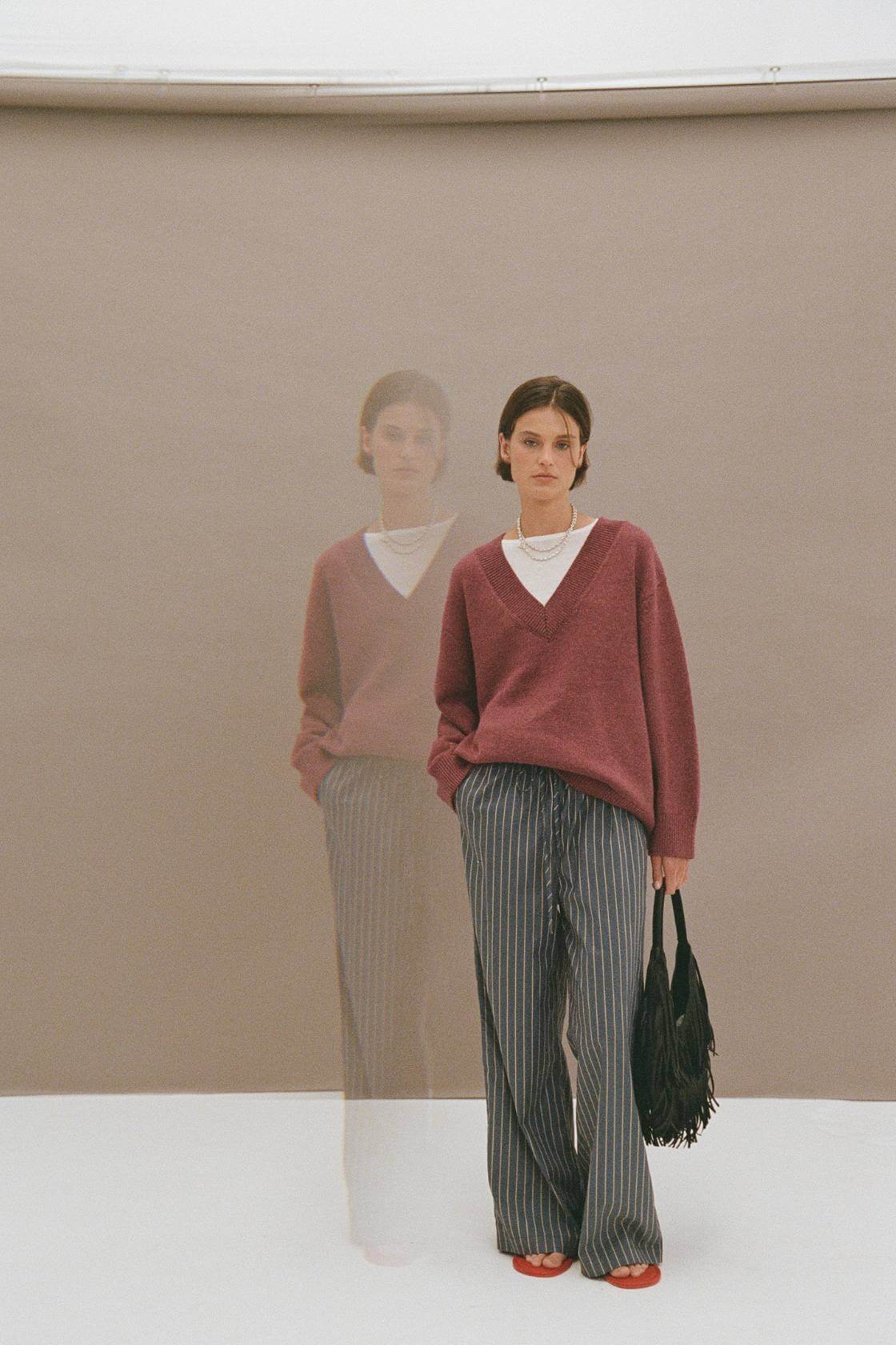 Lifestyle shot of merlot sweater styled with wide-leg pants