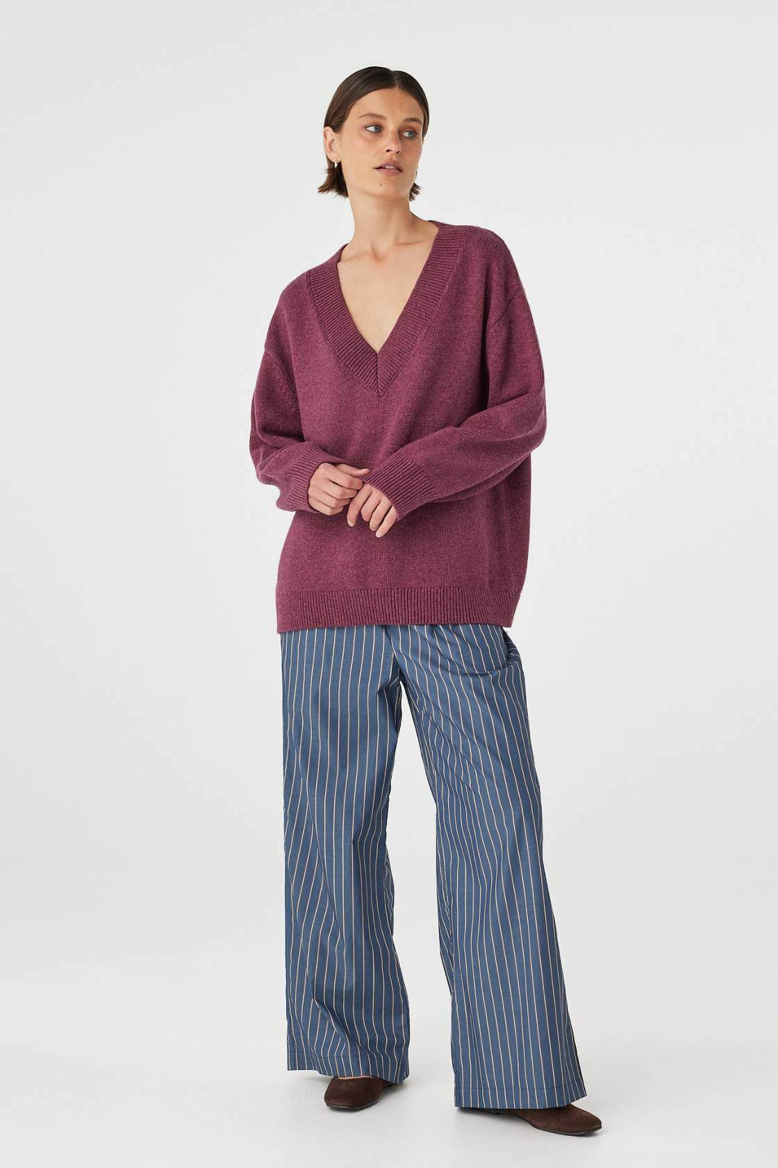 Front view of merlot sweater styled with hands together