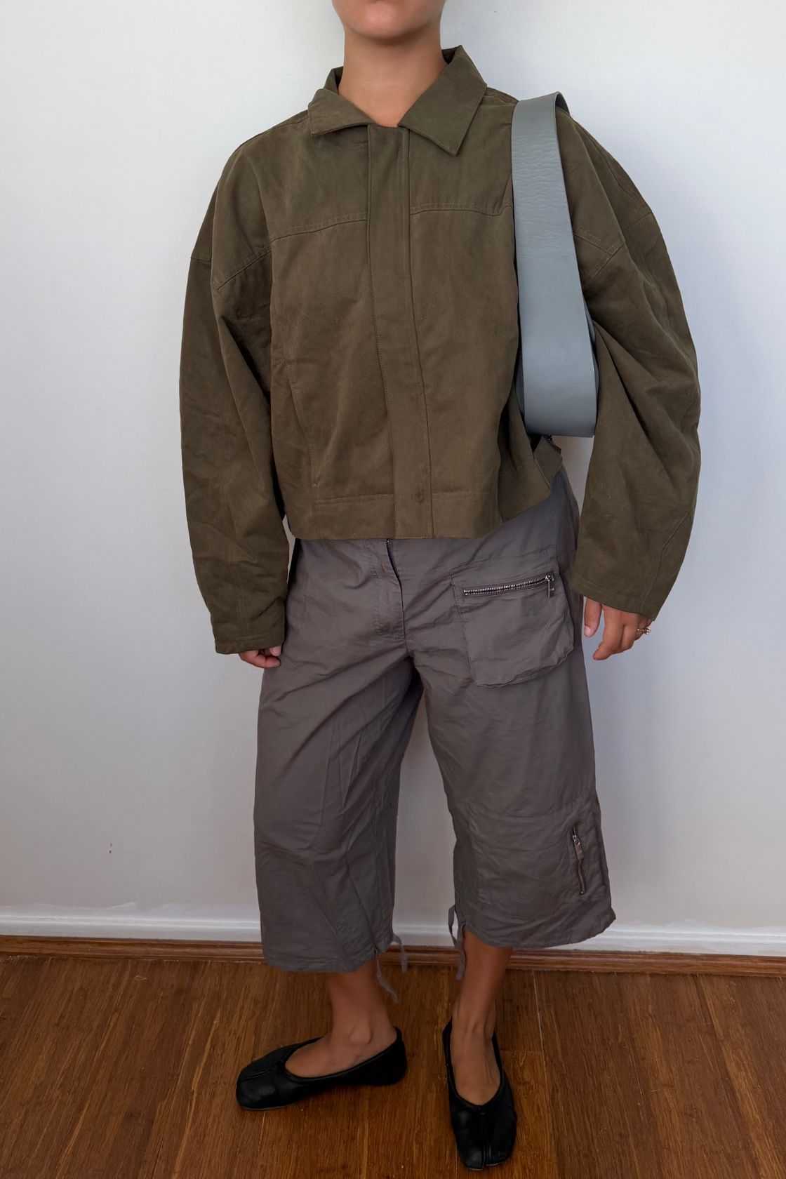 Cropped khaki jacket styled with knee-length shorts and ballet flats