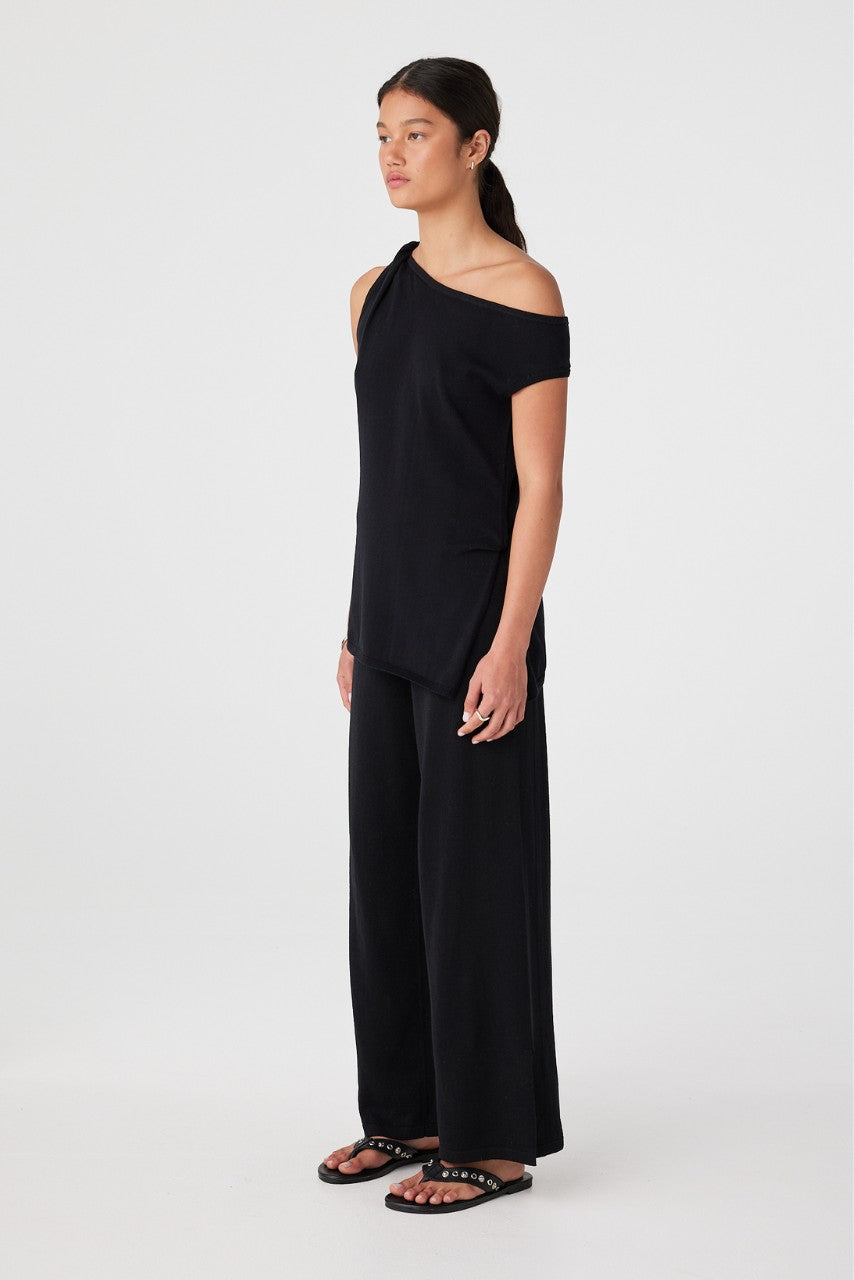 Side profile of woman in black relaxed wide-leg pants showing soft drape