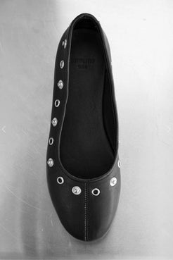 Close-up of black ballet flat showing stud and seam detail