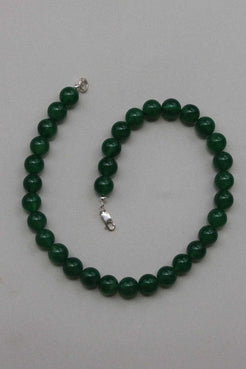 Green chalcedony gemstone necklace shown in a gentle curve, highlighting the round beads and silver clasp on a neutral surface.