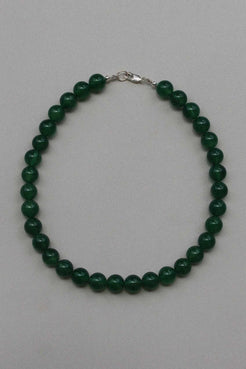 Green chalcedony beaded necklace with sterling silver clasp, laid in a circle on a soft grey background.