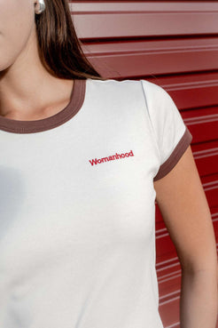 Womanhood embroidery detail on off white baby tee