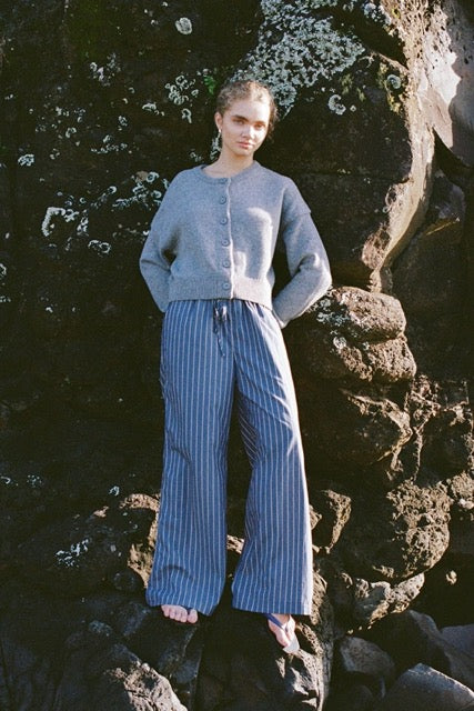 Blue striped pants and a grey sweater worn outdoors on rocks by the water