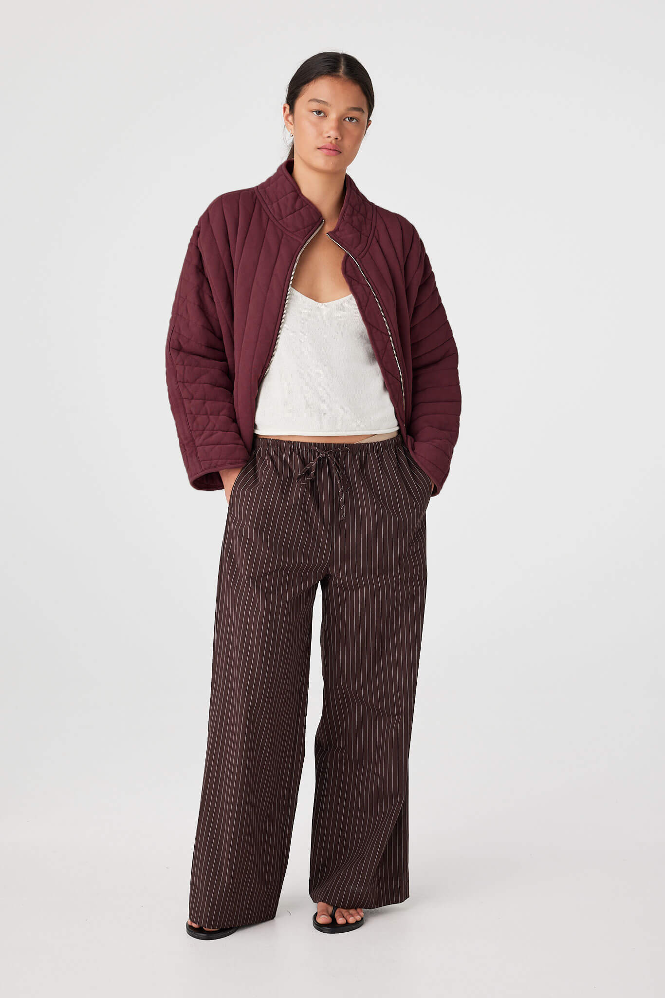 Model wearing Merlot quilted cotton jersey jacket with zip-through front and slouchy fit, styled with wide-leg pants for cool evenings