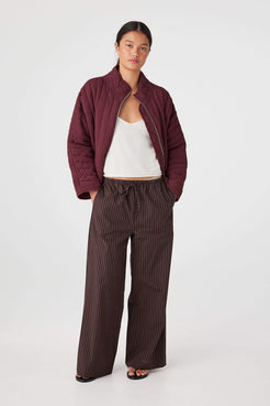 Model wearing Merlot quilted cotton jersey jacket with zip-through front and slouchy fit, styled with wide-leg pants for cool evenings