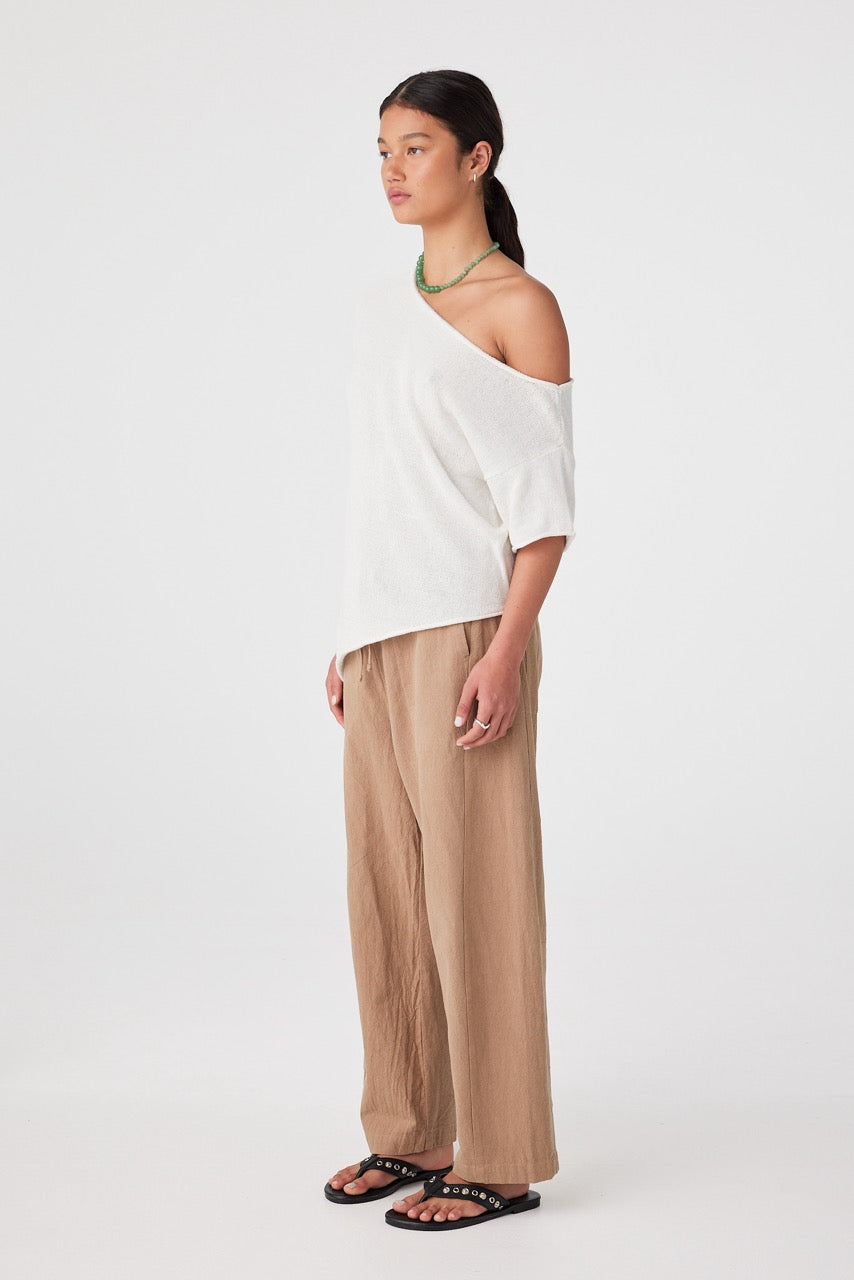 Three-quarter view of model wearing pecan barrel-leg pants styled with flat sandals