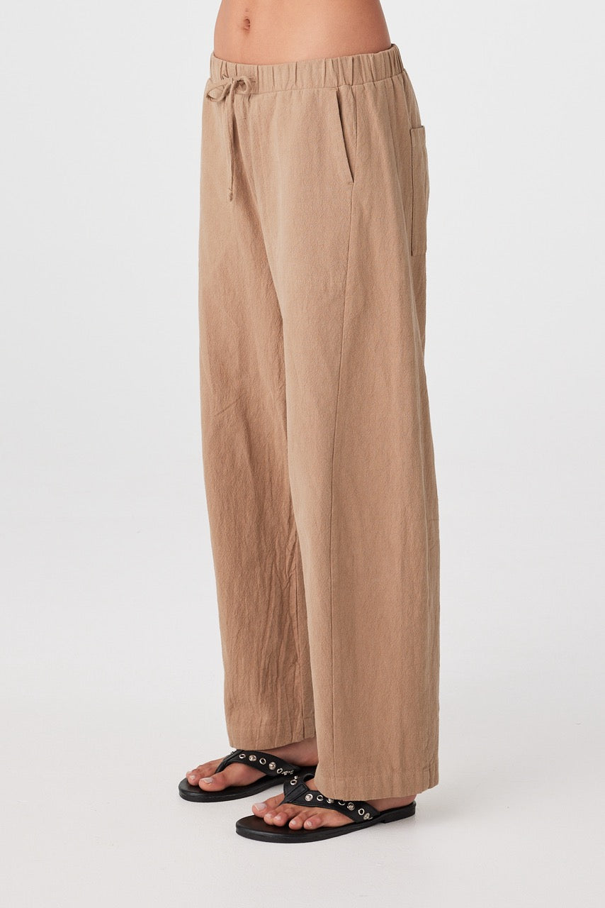 Side profile of woman in pecan barrel-leg pants with soft drape