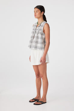 Three-quarter view of outfit with cream boxy shorts and check sleeveless top