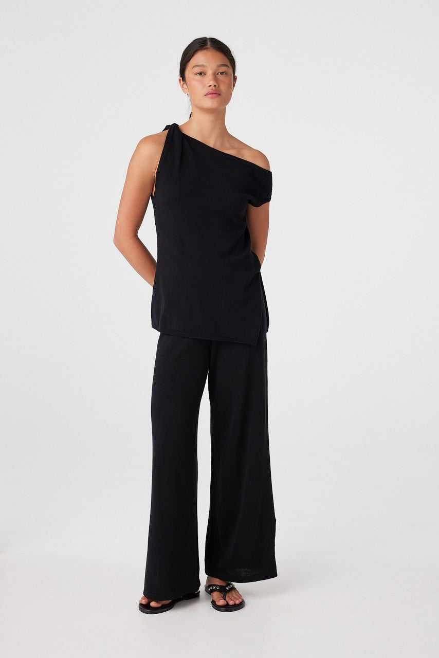 Front view of model wearing black Olympia asymmetrical one-shoulder cotton knit top with wide-leg pants