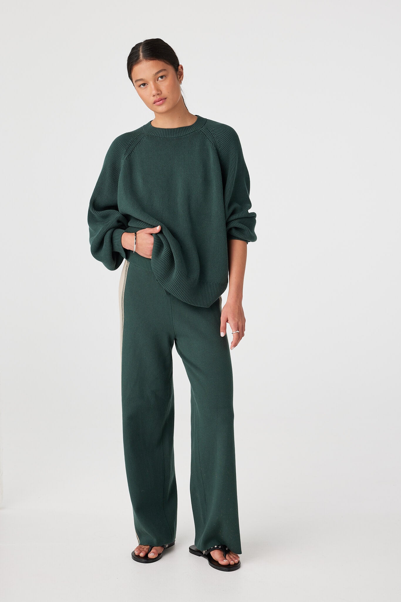 Model wearing Forest high-rise straight-leg pants with contrast side stripe and ribbed drawcord waist, styled with chunky knit sweater