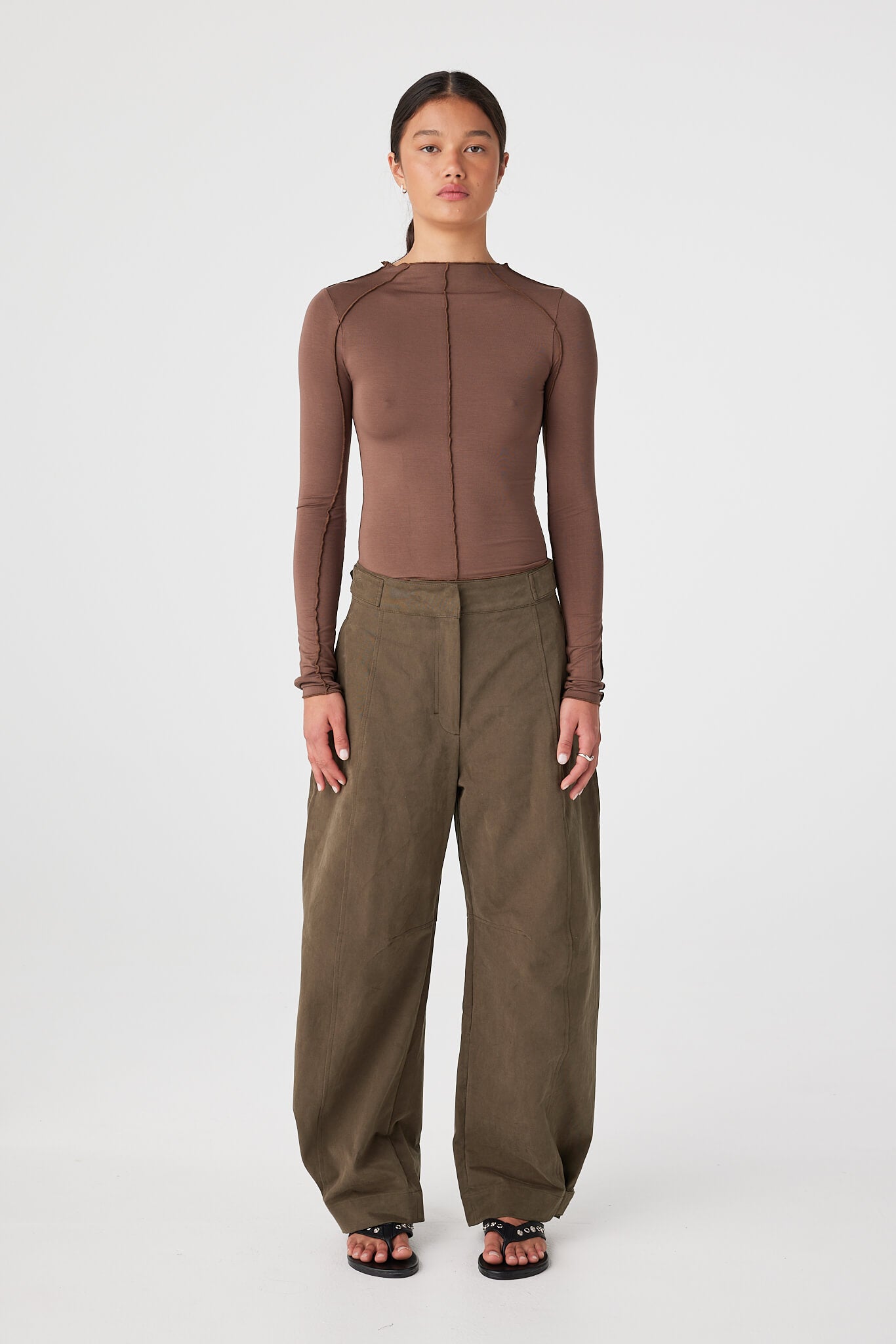Model wearing Espresso fitted bamboo jersey long sleeve top with funnel neck and tonal seam lines, styled with khaki barrel-leg pants