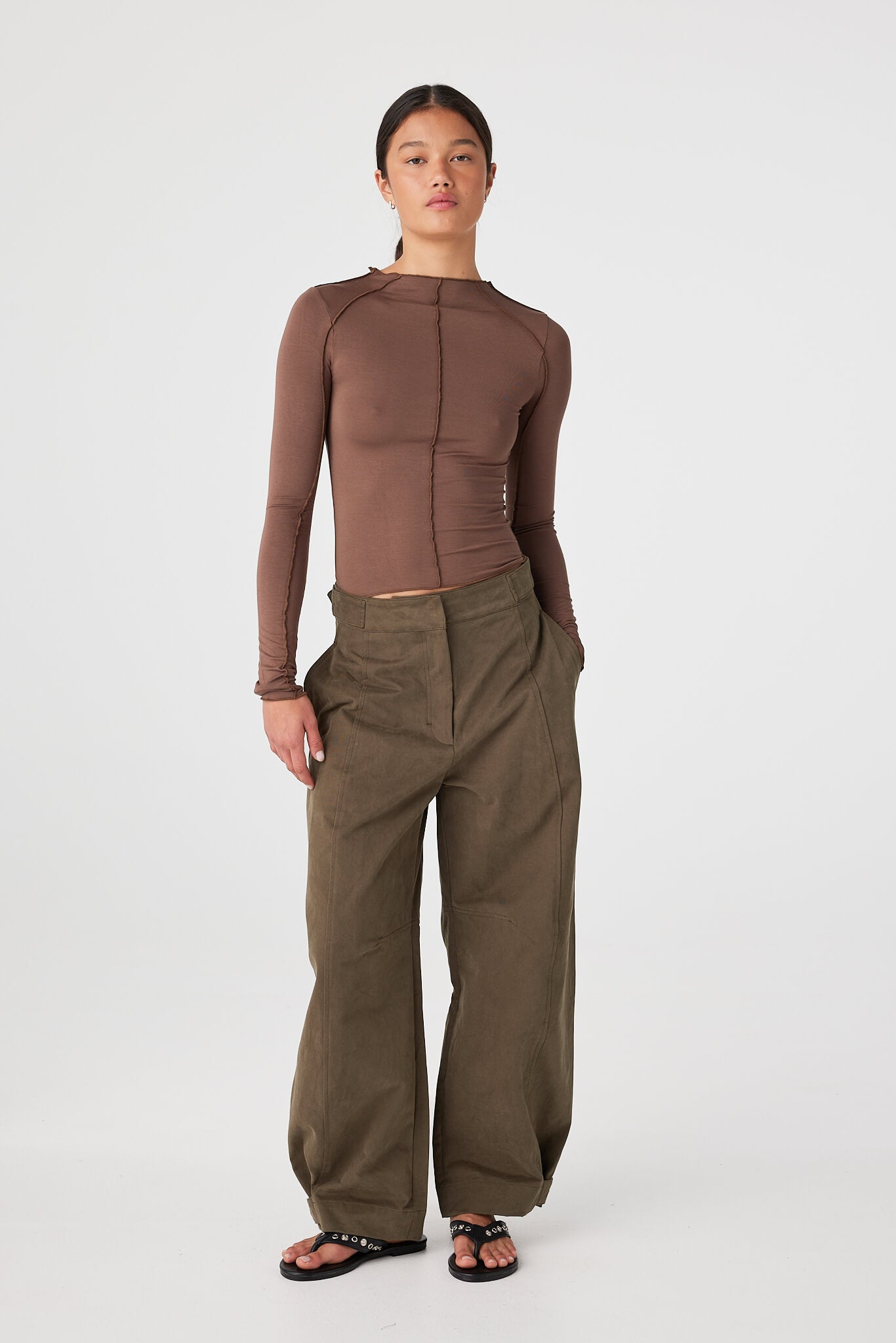 Khaki barrel-leg pants showing drape and movement in a structured cotton finish