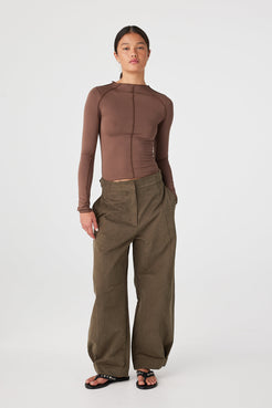Khaki barrel-leg pants showing drape and movement in a structured cotton finish