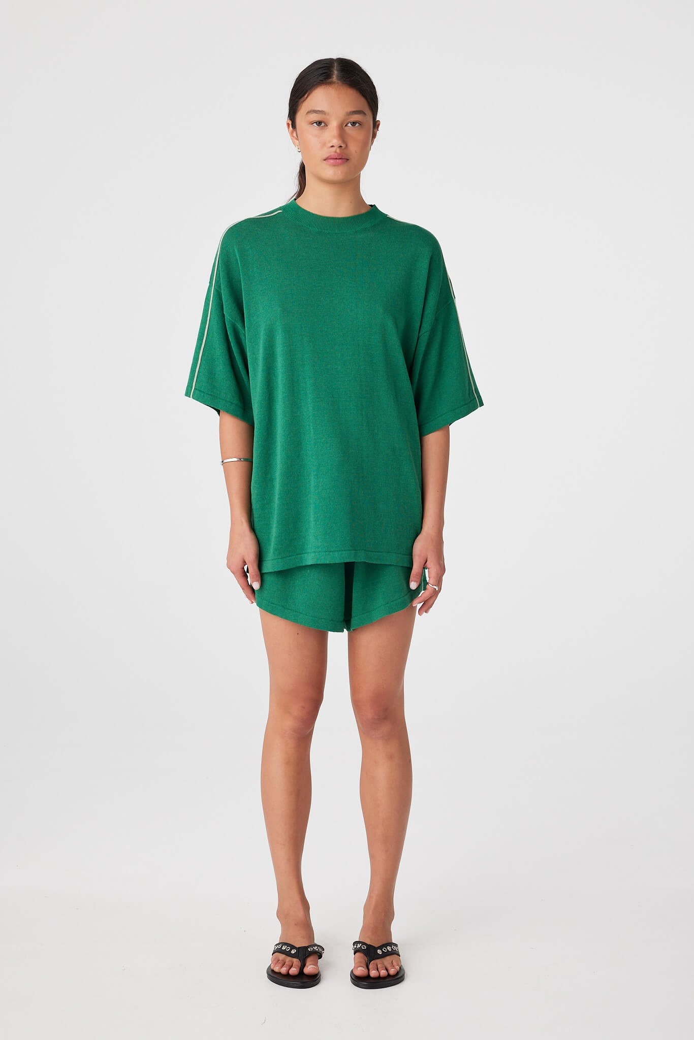 Model wearing sea green linen–cotton drawstring shorts with contrast side panels and relaxed fit.