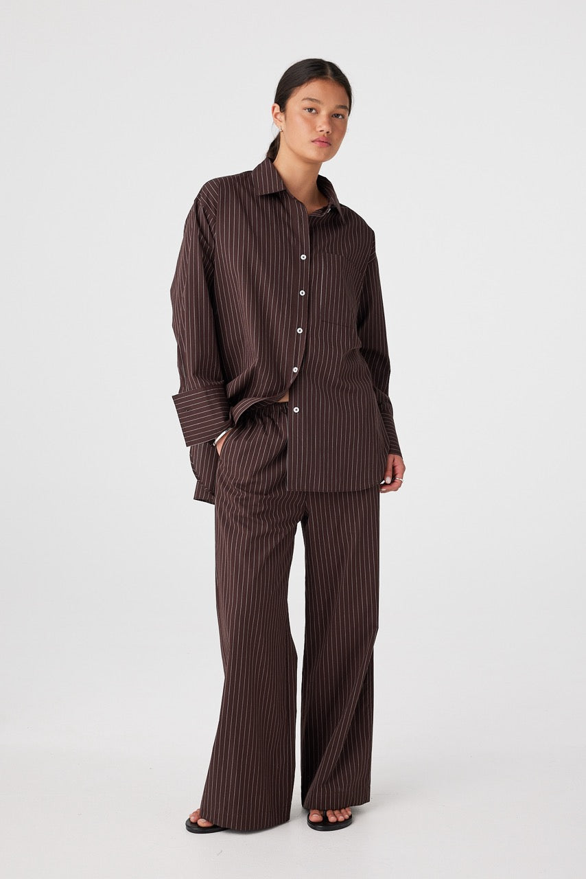 Model wearing relaxed cotton shirt with button front and wide leg pants in espresso stripe