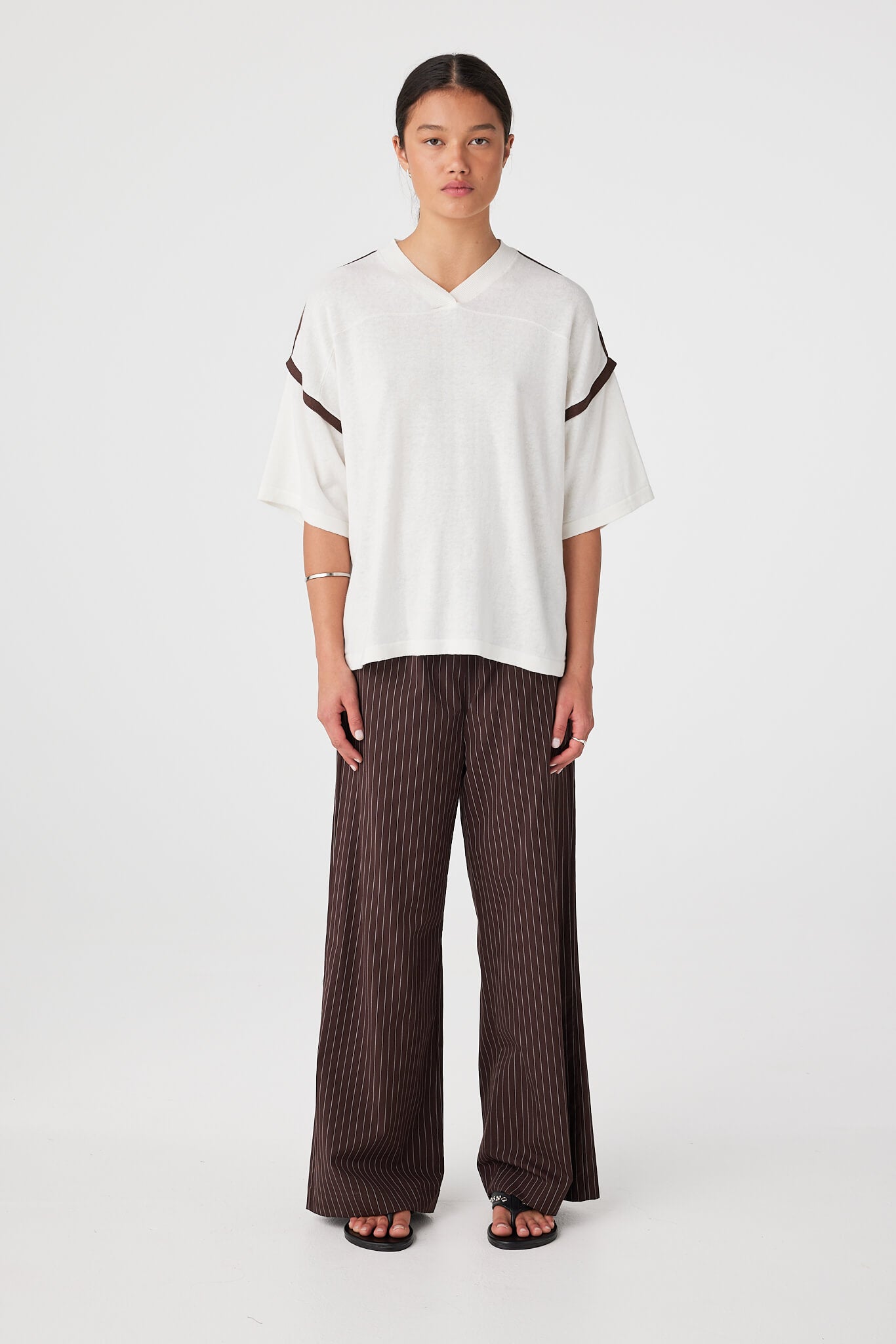 Front view of Cream oversized knit tee showing ribbed V-neckline and contrast stripe detail at shoulder