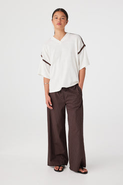 Model wearing Cream & Espresso oversized knit V-neck tee with contrast shoulder trim, styled with espresso pinstripe wide-leg pants