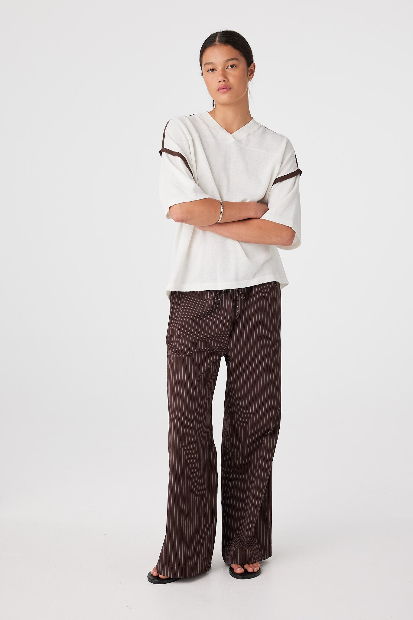 Full-body studio look: extra oversized slouchy knit tee in cream with espresso trim, paired with wide-leg pants for warm weather