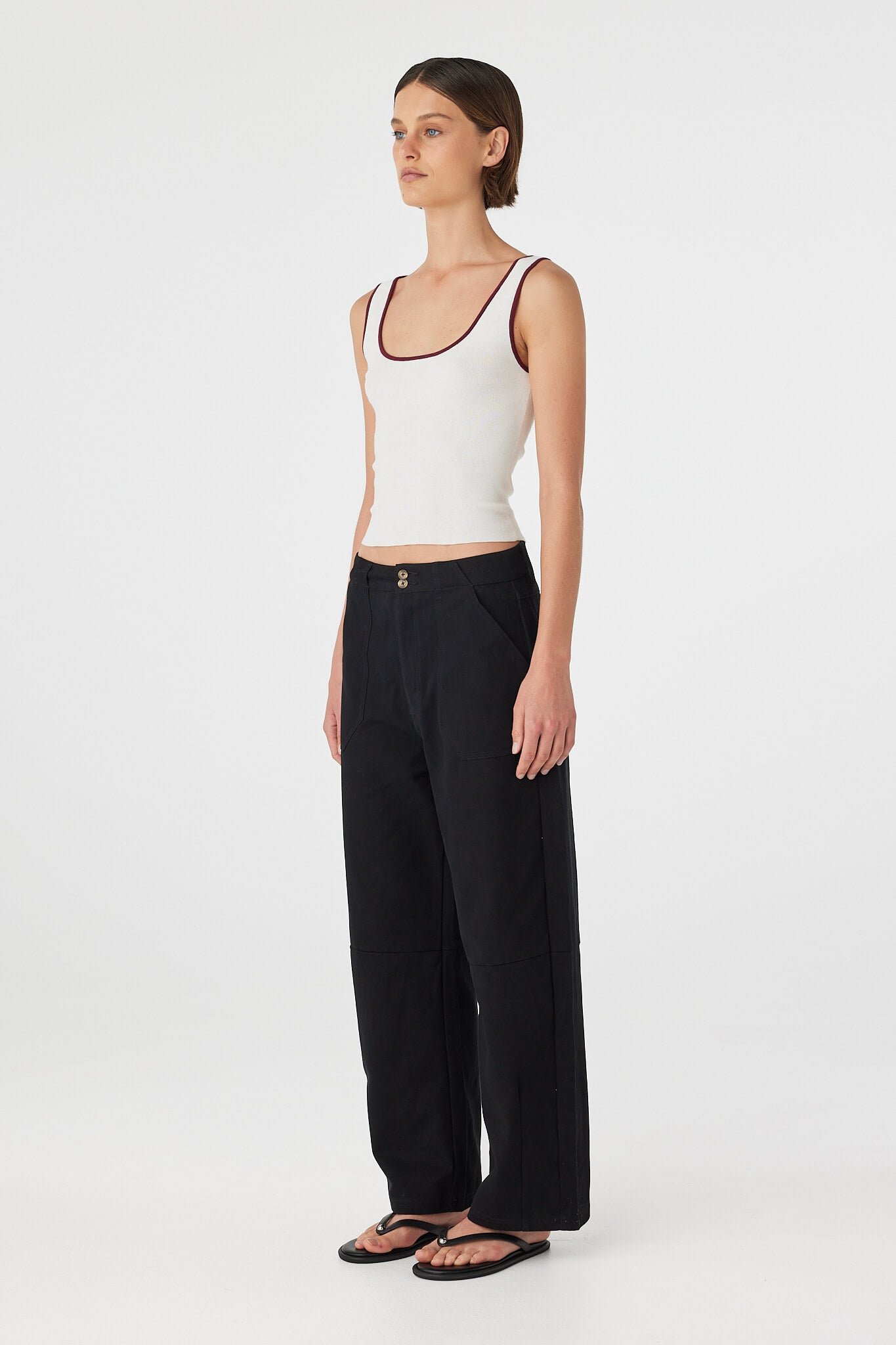 Side view of Akira Pant in black, relaxed cotton barrel-leg silhouette with belt loops and light structure through the leg.