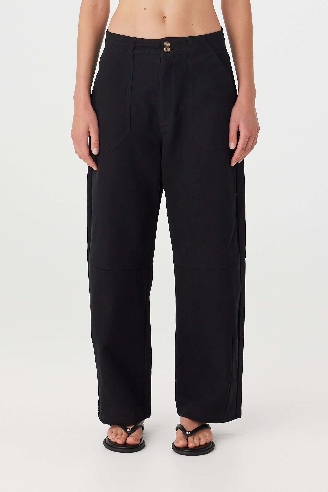 Akira Pant black cotton trousers on model, relaxed fit with gentle barrel leg shape, full length straight-on view.