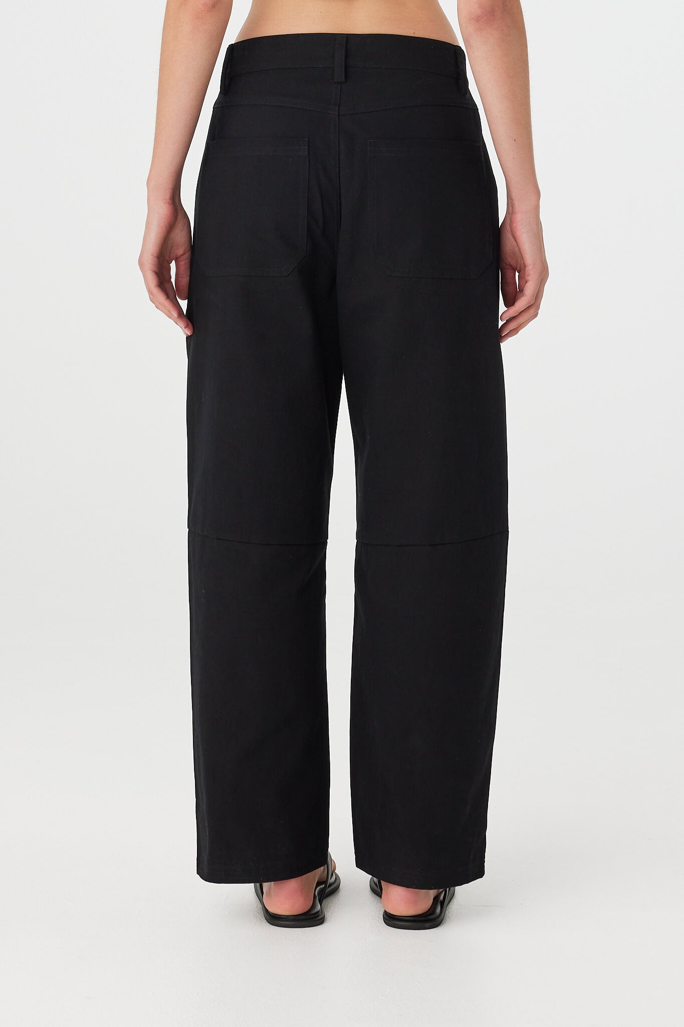 Akira Pant in black, relaxed full length cotton pant with gentle barrel leg, angled side view showing drape and volume.