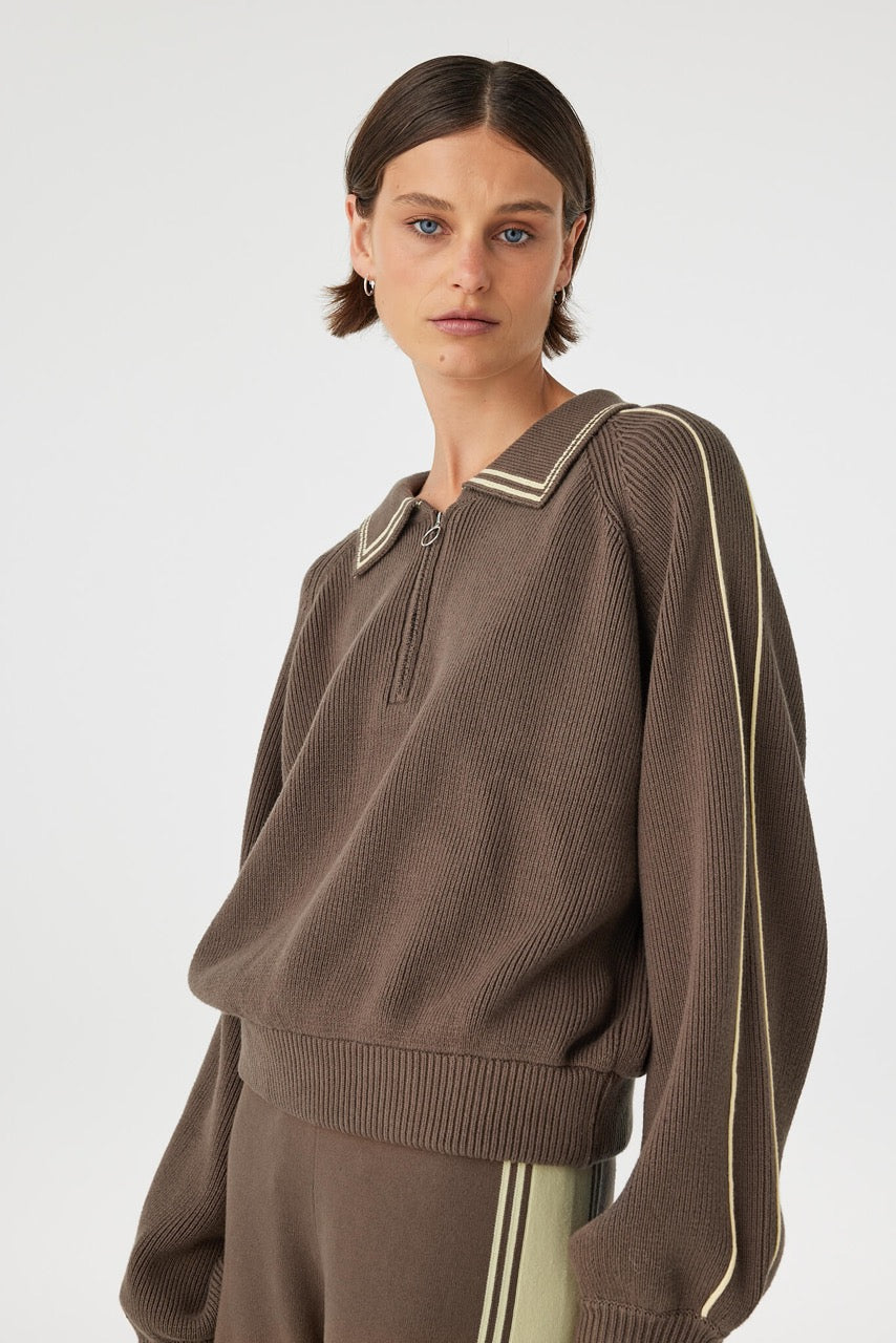 Angled front view of brown sweater showing sleeve piping and cuff detail