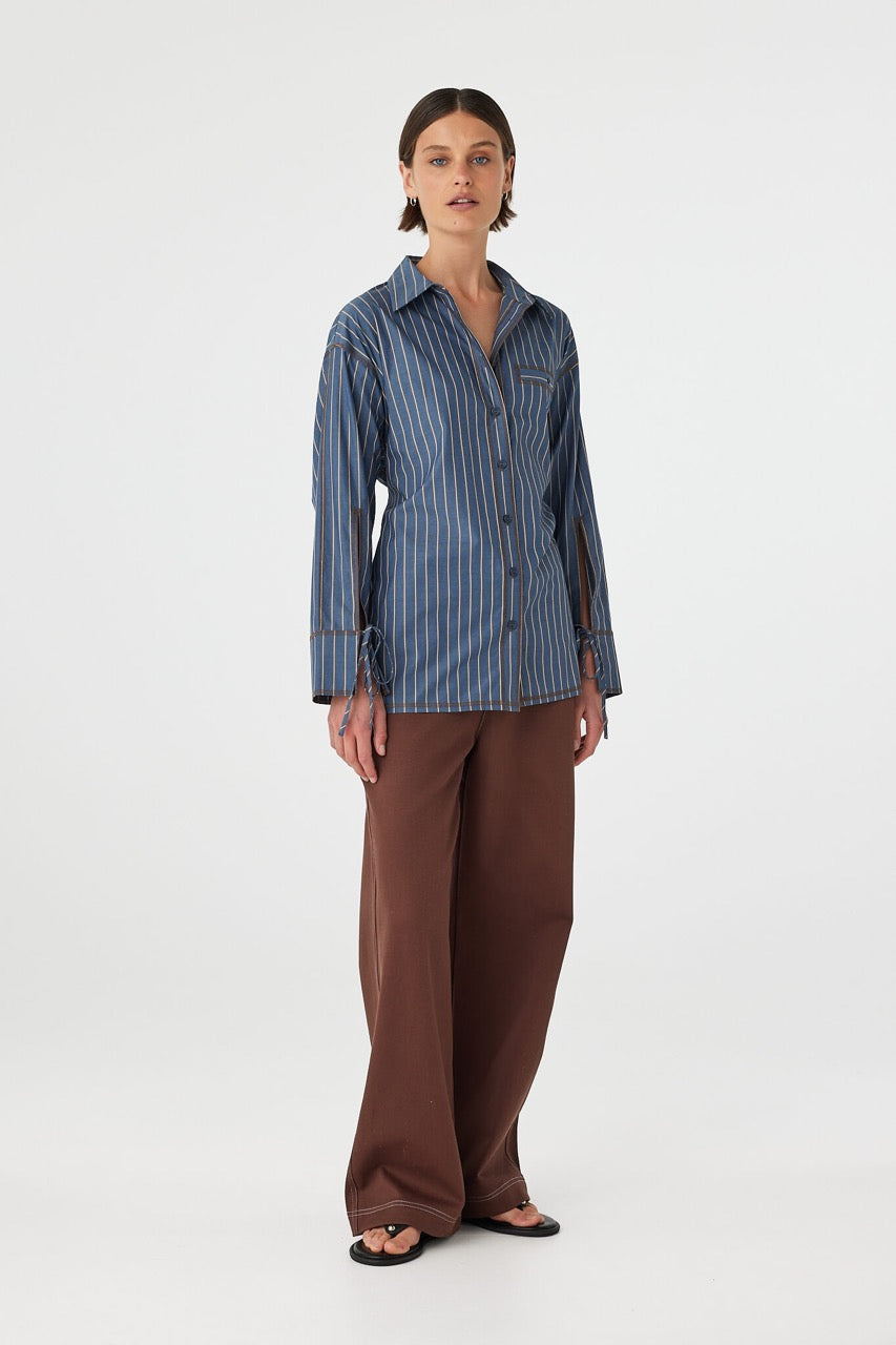 Three-quarter view of Blair Shirt muted blue stripe, relaxed cotton shirt worn loose with longline hem.