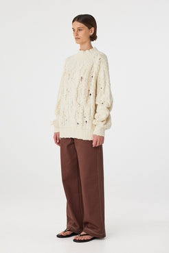 Side view of cream sweater with raglan sleeves and cuff detail