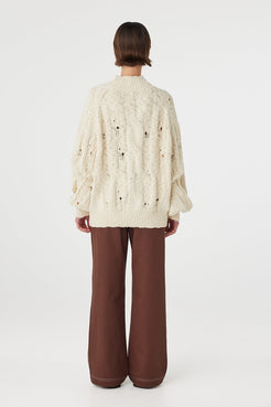 Back view of cream sweater with cable knit texture