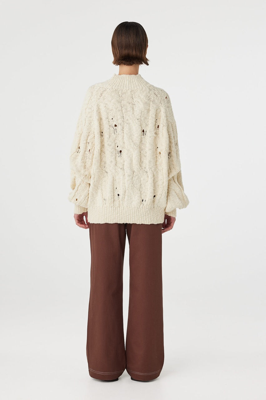 Back view of cream sweater with cable knit texture