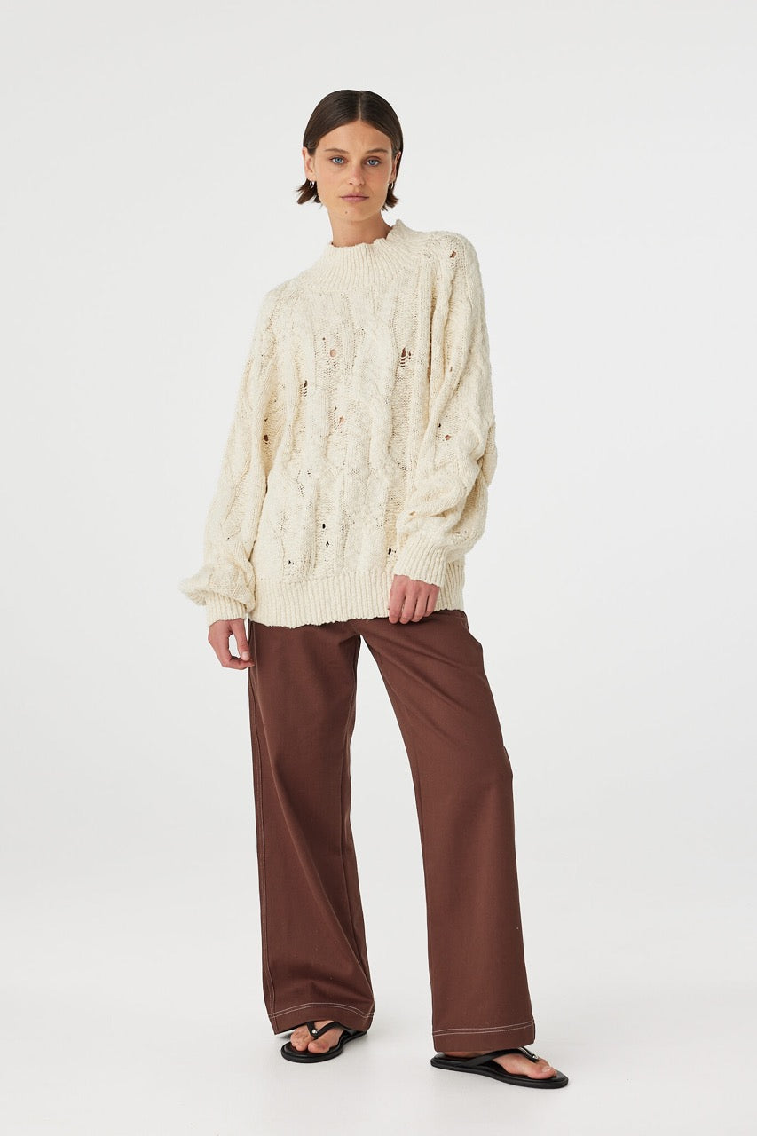 Angled front view of cream sweater showing funnel neck and relaxed shape